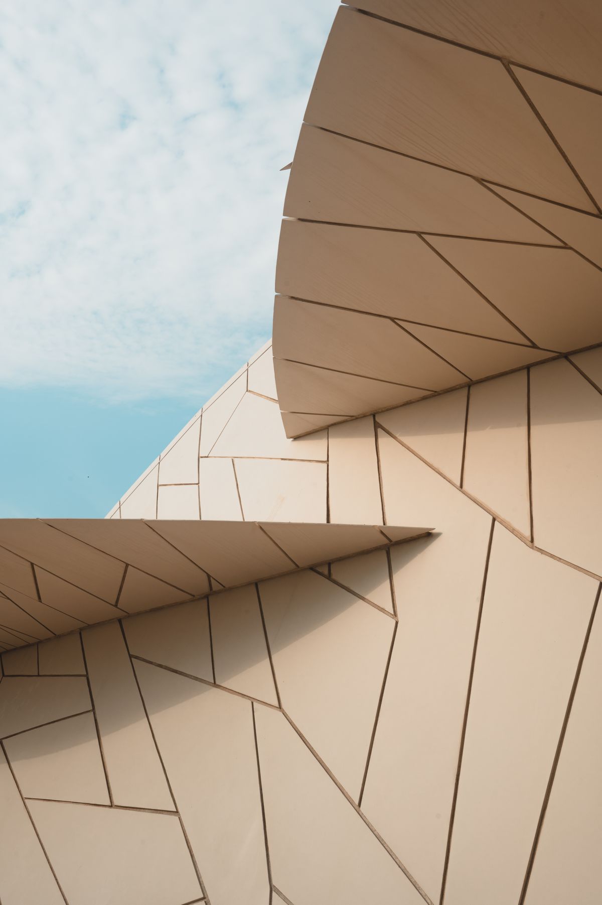 Warm stone-colored architectural facade with sculptural geometric panels