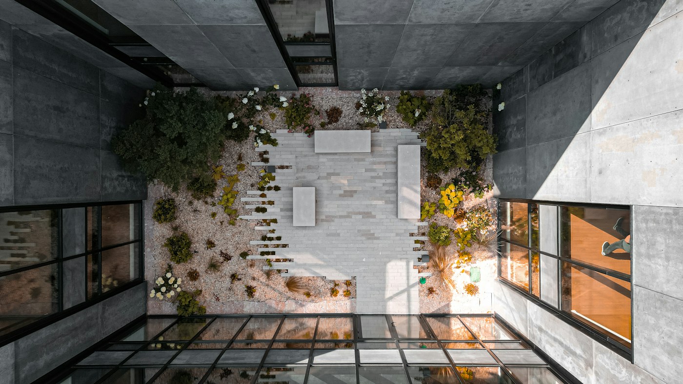 Landscaped courtyard framed by concrete walls and floor-to-ceiling windows