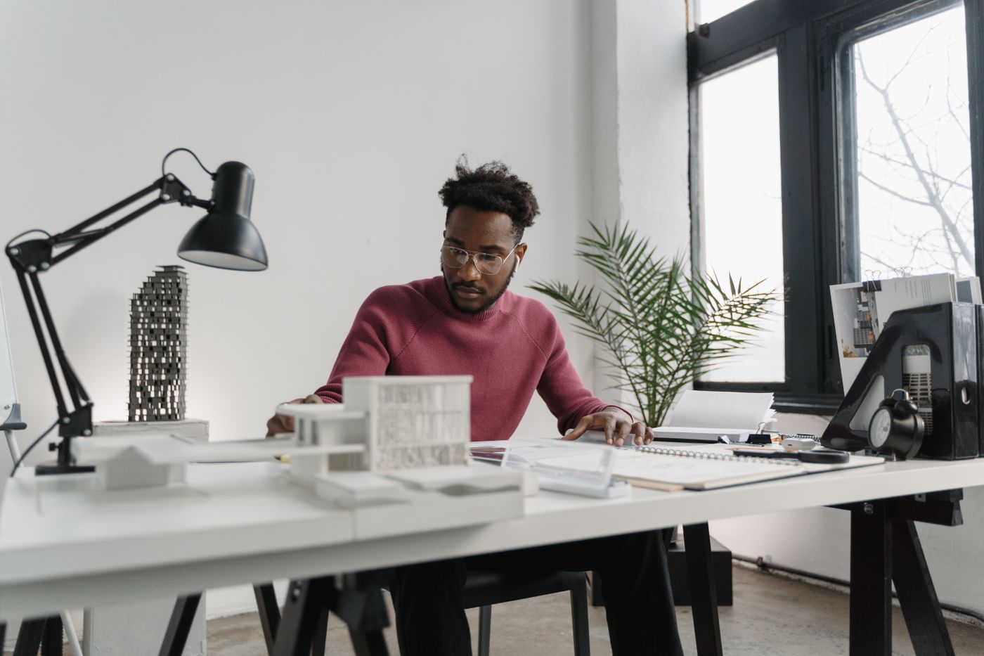 Architect working at a bright studio desk with drawings and architectural models