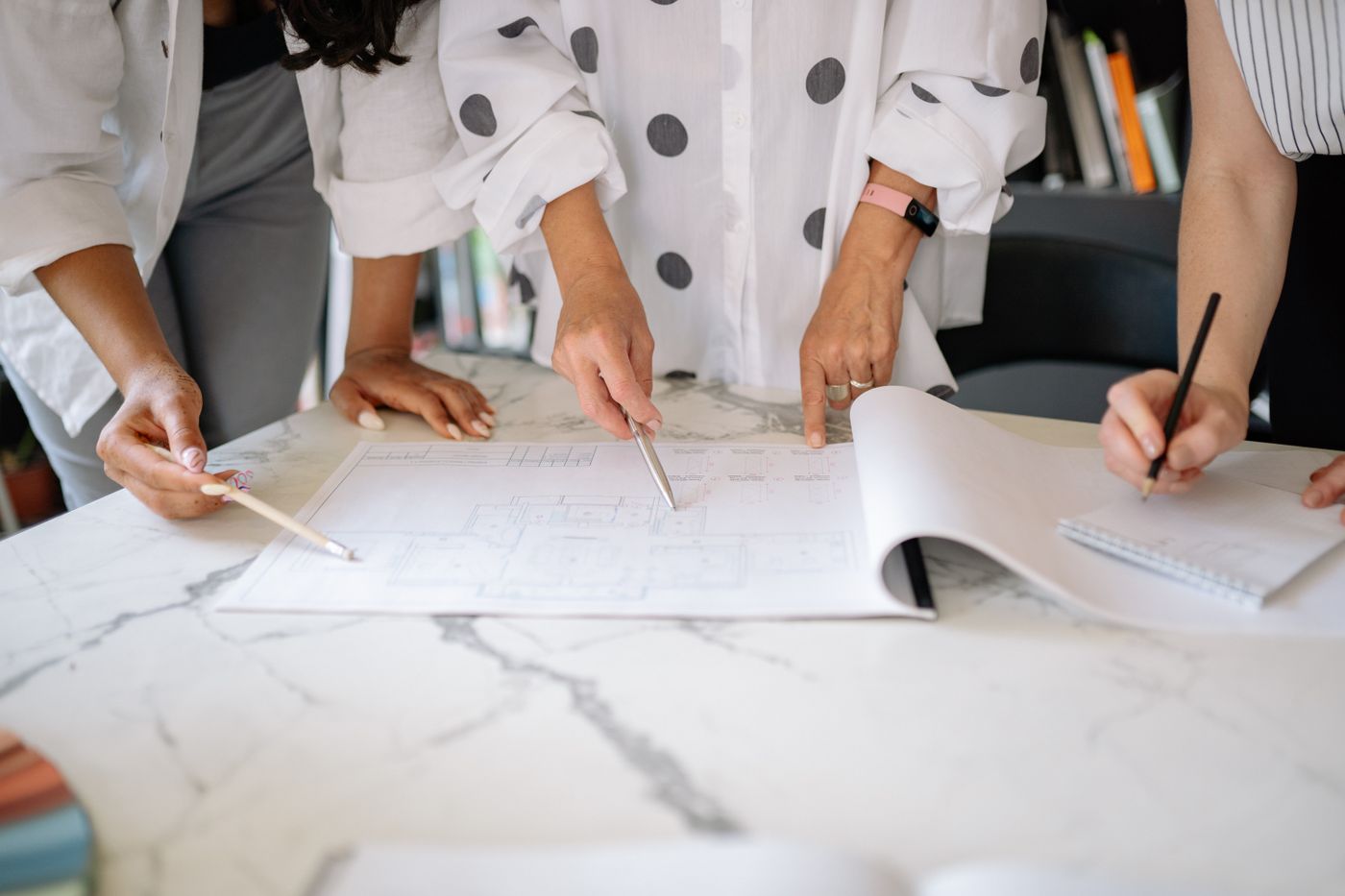 A small team marking up architectural plans around a studio table